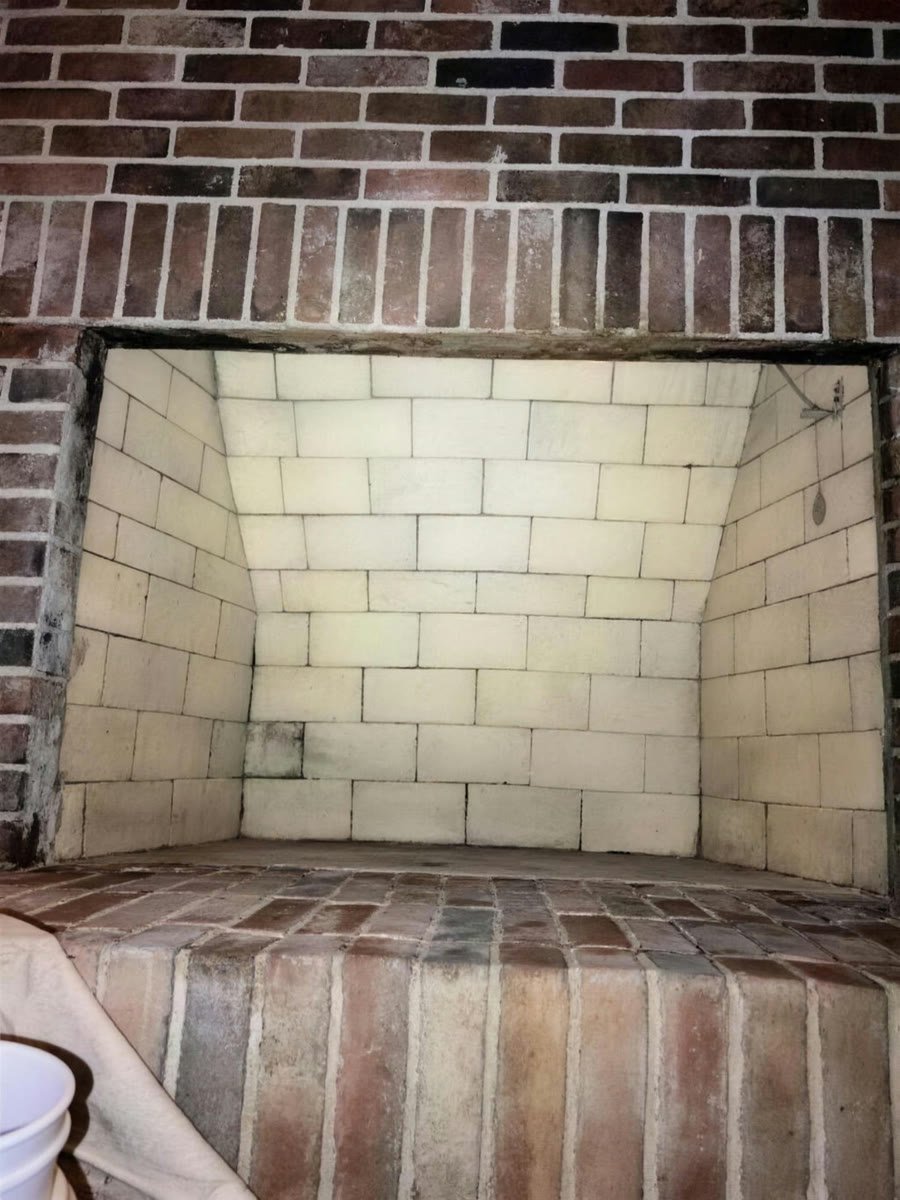 Fireplace firebox rebuilt in new tan firebrick inside a red brick surround