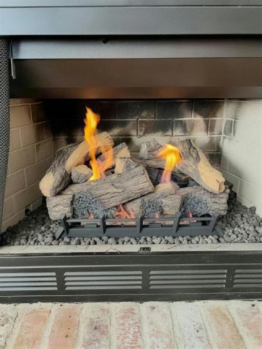 Gas log set burning in a fireplace above a brick hearth